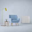Gloss white designer flat panel radiator, 600mm x 700mm, sleek and modern, complements a cozy blue armchair and stylish decor