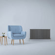 Anthracite grey designer flat panel radiator, sleek vertical lines, modern design, placed beside a light blue armchair and wooden table