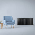 Sleek matt black flat panel radiator, 600mm x 1400mm, paired with a light blue armchair and wooden side table in a modern setting