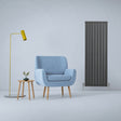Sleek anthracite grey flat panel radiator, 1600mm x 560mm, paired with a modern blue armchair and stylish yellow floor lamp in a minimalist setting