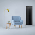 Sleek matt black designer flat panel radiator stands tall beside a modern blue armchair and stylish yellow floor lamp in a minimalist setting