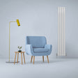 Gloss white designer flat panel radiator, 1800mm x 280mm, positioned beside a blue armchair and modern floor lamp in a minimalist setting
