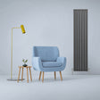 Anthracite grey designer flat panel radiator stands tall beside a blue armchair and a modern lamp, enhancing a stylish interior