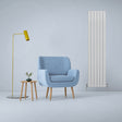 Gloss white designer flat panel radiator, 1800mm x 420mm, stands tall beside a cozy blue armchair and stylish floor lamp in a modern room