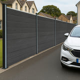 Grey composite fence panels with angled pieces and LED posts, showcasing a sleek, modern design along a residential street