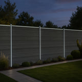 Grey composite fence panels with angled pieces and illuminated LED posts, set against a dark evening sky and landscaped garden