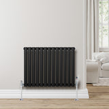 Sleek black oval single column radiator with chrome valves, mounted on a light wall, enhancing modern interior decor
