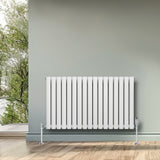 Sleek white oval single column radiator with chrome valves, positioned against a soft green wall, enhancing modern interior decor