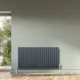 Anthracite grey oval single column radiator with sleek vertical bars, mounted on the wall, enhancing modern interior decor