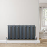 Anthracite grey oval single column radiator with sleek vertical lines, mounted on a light wall, complementing a cozy living room setting