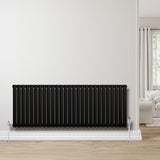 Sleek black oval single column radiator with chrome valves, mounted on a light wall, enhancing modern interior decor and warmth