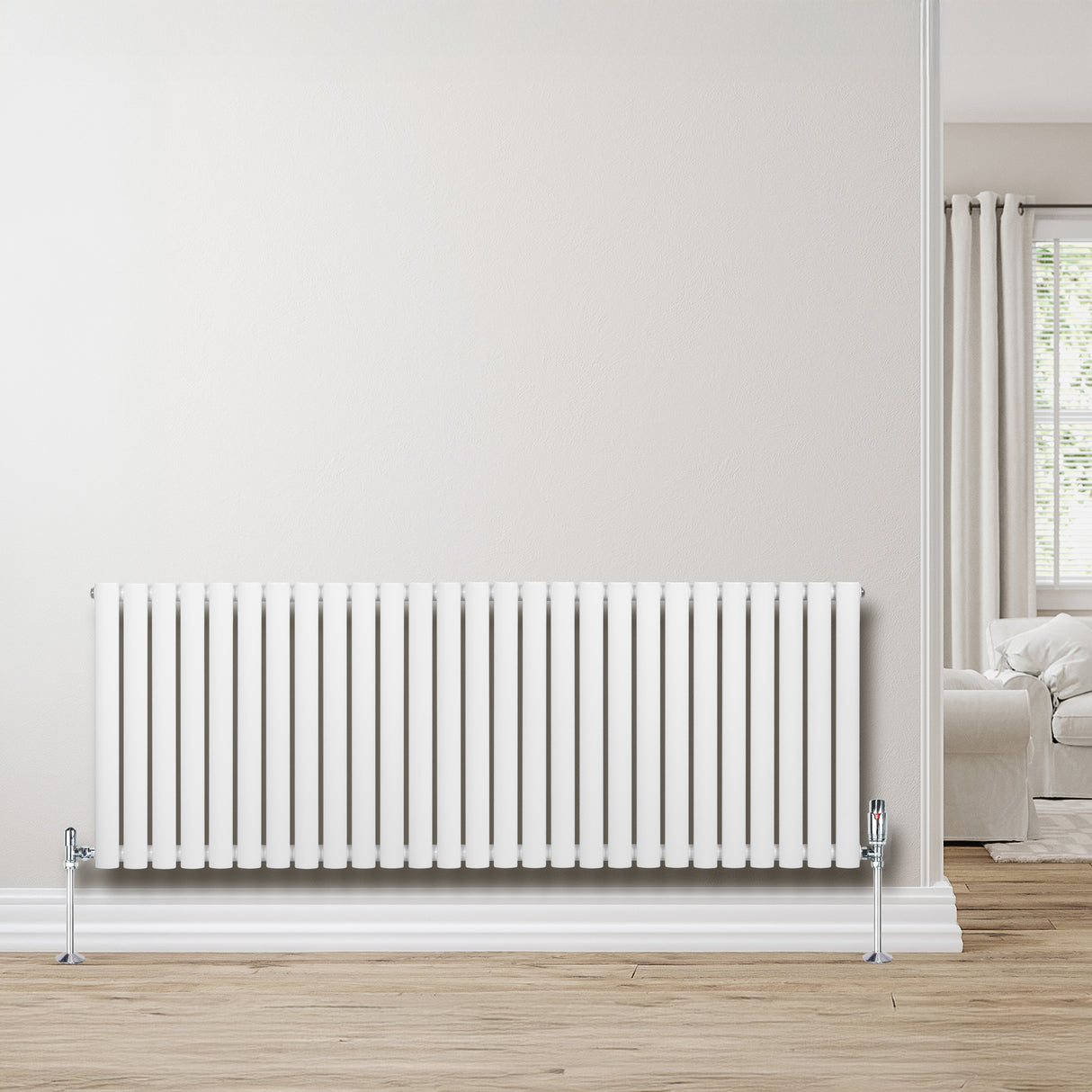 Sleek white oval single column radiator with chrome valves, set against a light wall and wooden floor, enhancing modern decor