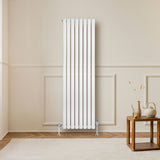 Sleek white oval single column radiator stands tall against a neutral wall, enhancing a cozy living space with elegant design