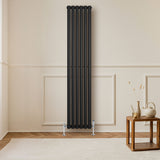 Sleek black oval single column radiator with polished valves, positioned against a light wall, enhancing modern interior decor