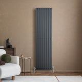 Sleek anthracite grey oval single column radiator mounted on a textured beige wall, enhancing modern interior decor with elegant lines