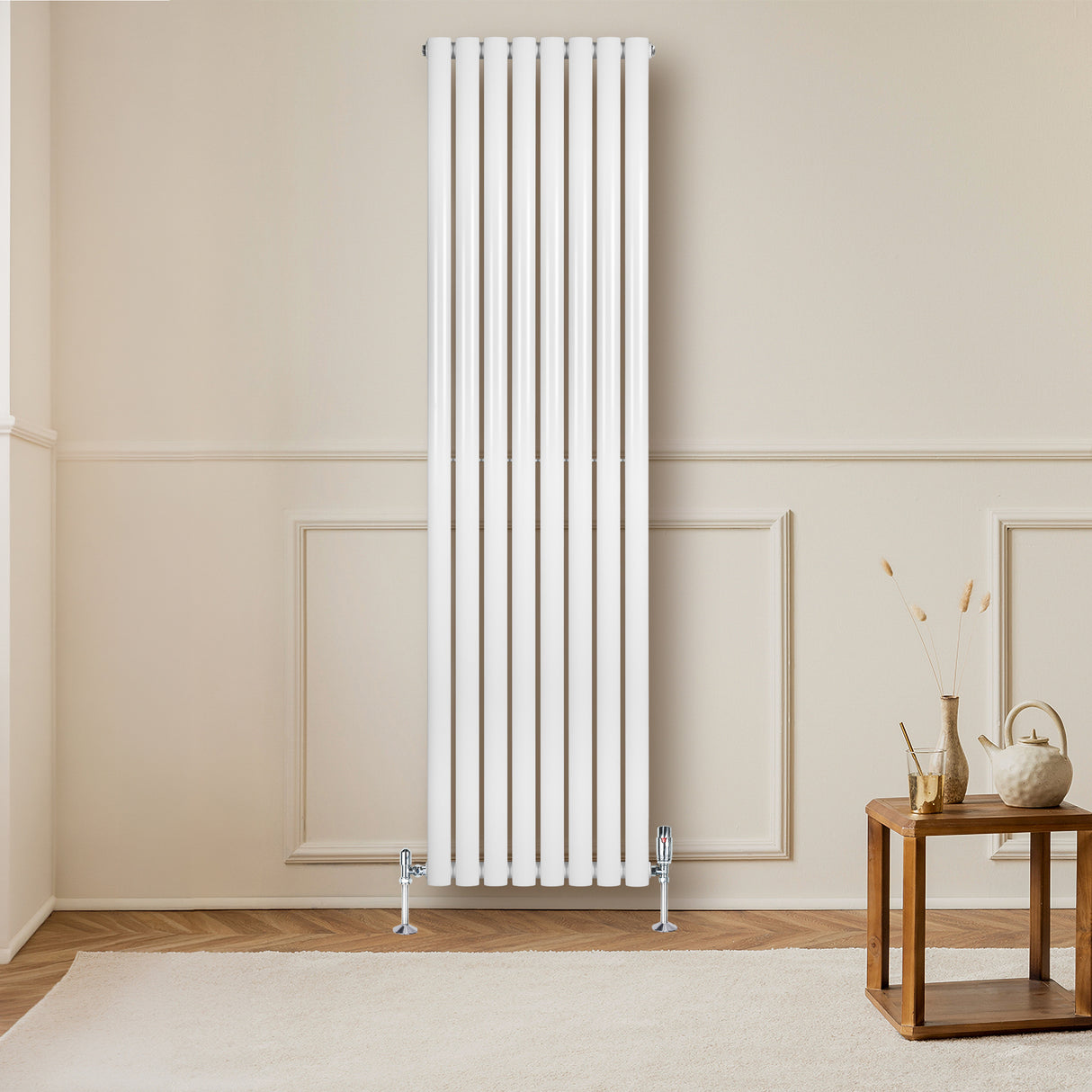 Sleek white oval single column radiator with vertical bars, mounted on a light wall, complemented by stylish valves and wooden furniture