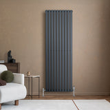 Sleek anthracite grey oval single column radiator mounted on a textured wall, complemented by stylish valves and modern decor