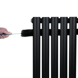 Black oval single column radiator with smooth, matte finish, being cleaned with a brush, showcasing its sleek design and modern appeal