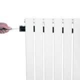 White flat single column radiator with smooth, sleek panels, being cleaned with a brush for maintenance and efficiency