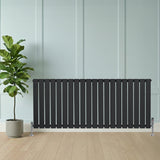 Flat single column radiator in anthracite grey, featuring vertical slats, sleek design, and positioned beside a potted plant on wooden flooring