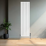 Sleek white flat single column radiator with chrome valves, standing tall against a minimalist wall, complemented by a potted plant