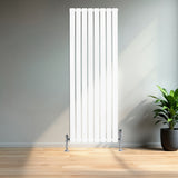 Sleek white flat single column radiator with vertical bars, chrome valves, and a modern design, set against a minimalist interior with a plant