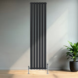 Tall anthracite grey flat single column radiator with sleek vertical lines and chrome valves, set against a minimalist interior backdrop