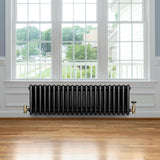 Traditional black 4 column radiator with brass valves, positioned under a large window, enhancing a warm, classic interior design