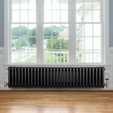 Traditional black 4 column radiator with brass valves, positioned under a large window, showcasing a sleek, vintage design