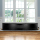 Traditional black 4 column radiator with brass valves, positioned below a large window, enhancing a modern interior space