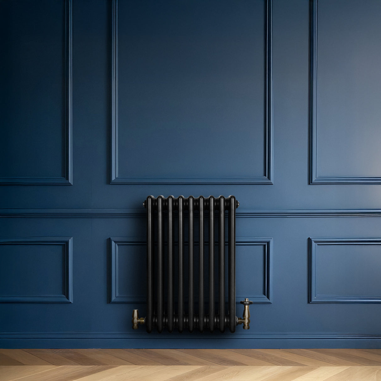 Traditional black 4 column radiator with brass valves mounted on a deep blue wall, featuring a sleek, vintage design and smooth finish