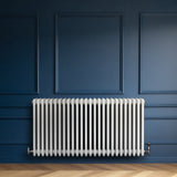 Traditional white 4 column radiator with a sleek design, mounted against a dark blue wall, enhancing modern interior aesthetics
