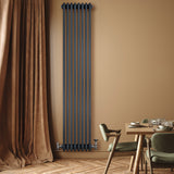 Traditional anthracite grey 4 column radiator with valves, mounted on a warm-toned wall, complementing a cozy dining area