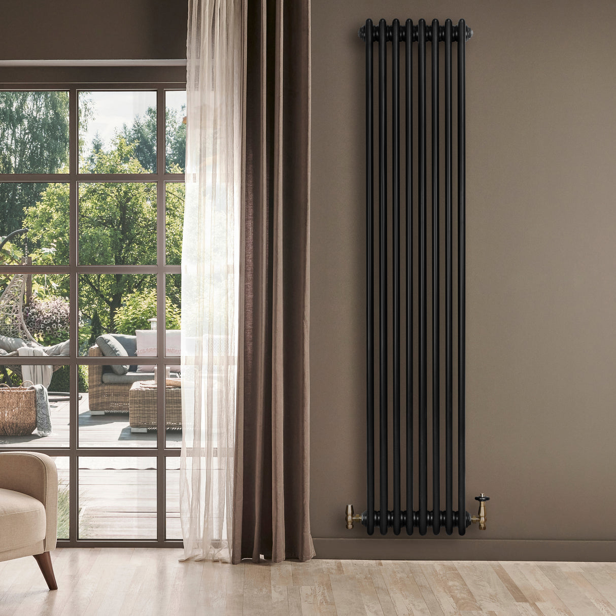 Traditional black 4 column radiator with brass valves, mounted on a beige wall, enhancing a modern living space with natural light