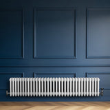 Traditional white 4 column radiator with a sleek design, mounted on a blue wall, enhancing a modern interior space