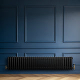 Traditional black 4 column radiator, 300 x 1505mm, installed against a deep blue wall, showcasing a sleek, modern design and elegant finish