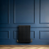 Traditional black 4 column radiator mounted on a deep blue wall, featuring a sleek, smooth finish and elegant brass valves