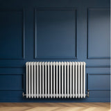 Traditional white 4 column radiator with a sleek design, mounted on a dark blue wall, showcasing smooth, glossy finish and elegant lines