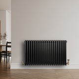 Traditional black 4 column radiator, 600 x 1010mm, featuring a sleek, glossy finish and brass fittings, mounted on a light wall
