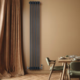 Tall anthracite grey traditional 4 column radiator mounted on a warm beige wall, complementing a stylish dining area with wooden flooring