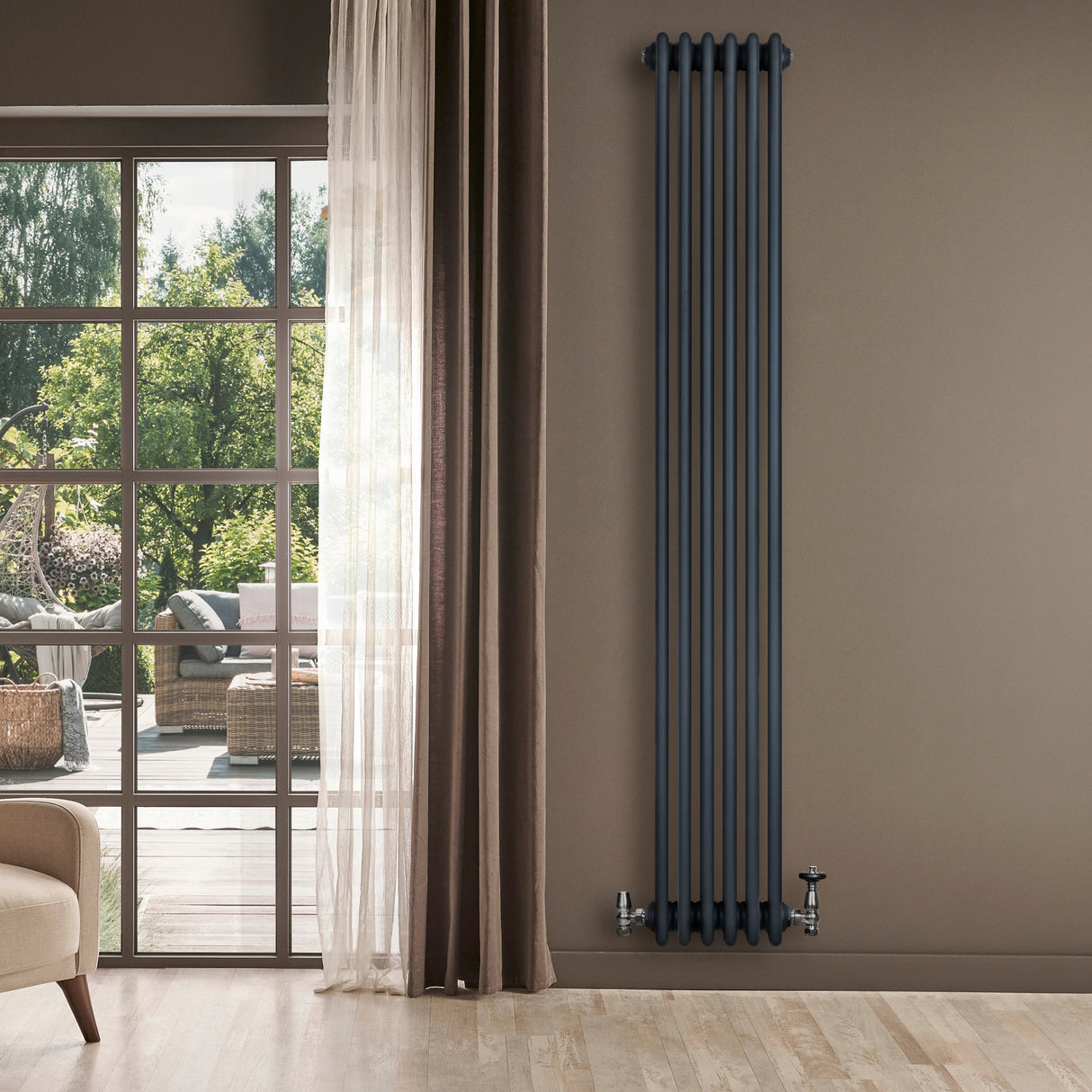 Tall anthracite grey traditional 4 column radiator with sleek vertical design, mounted on a wall beside large windows and curtains