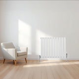Sleek white flat single column radiator, 600 x 700mm, positioned beside a modern armchair in a bright, minimalistic room