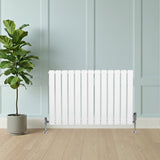 Sleek white flat single column radiator with vertical slats, positioned beside a potted plant against a light blue wall