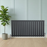 Flat single column radiator in anthracite grey, featuring sleek vertical slats, positioned against a light wall with a potted plant nearby