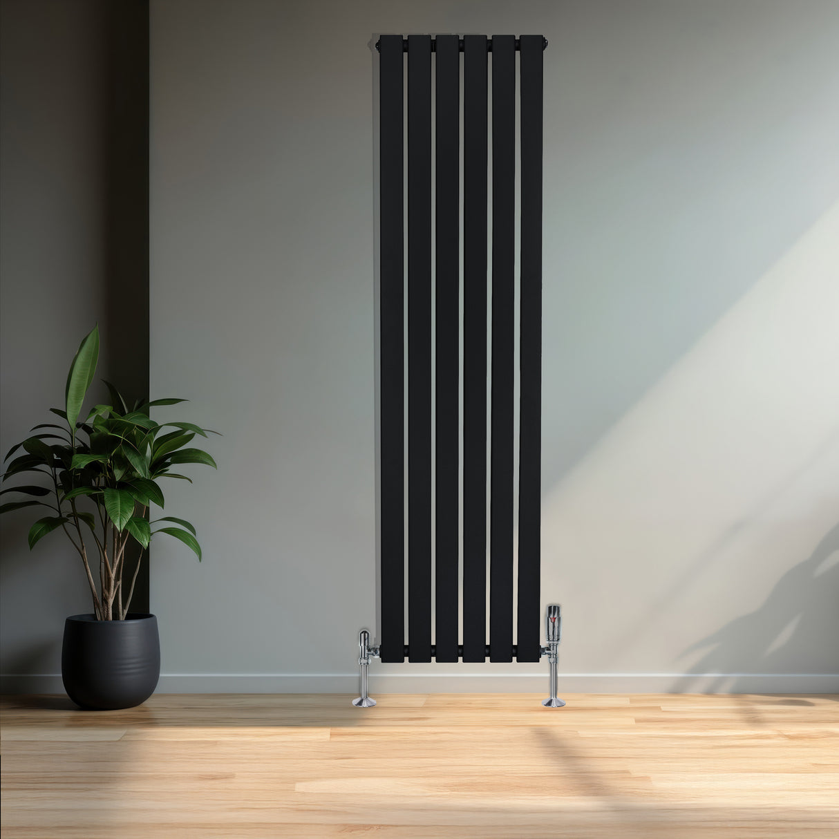Sleek black flat single column radiator stands tall against a light wall, complemented by chrome valves and a potted plant nearby