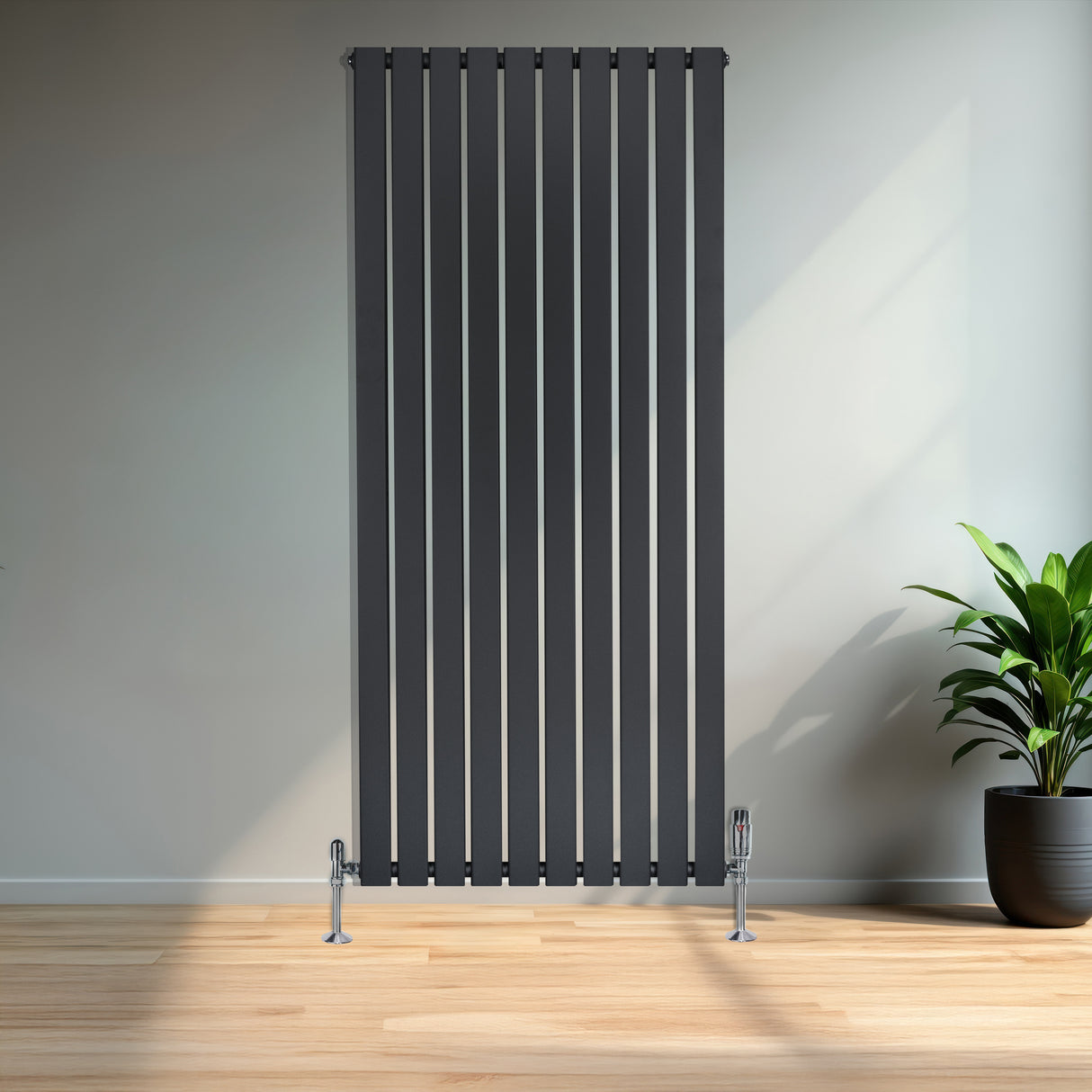 Flat single column radiator in anthracite grey, featuring vertical slats and sleek chrome feet, set against a modern interior with a plant