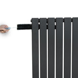 Flat single column radiator in anthracite grey, featuring sleek vertical lines and a hand adjusting the valve at the top