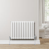 Sleek white oval single column radiator, 600 x 780mm, mounted on a light wall, with chrome valves and a modern living room backdrop