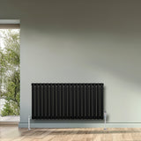 Sleek black oval single column radiator, 600 x 1200mm, mounted on a wall with a modern design, enhancing a stylish interior space