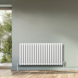 Sleek white oval single column radiator, 600 x 1200mm, mounted on a wall, complementing a modern interior with natural light